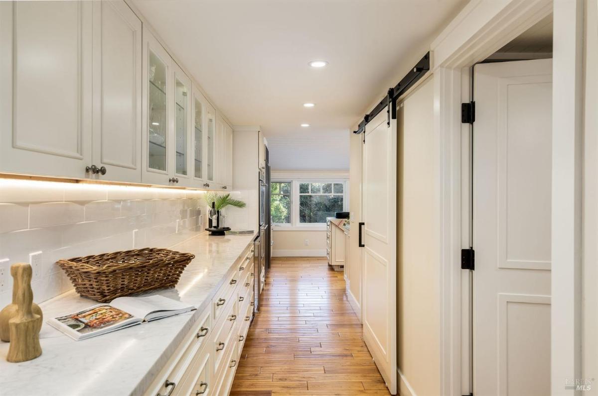 A hallway with cabinets, a countertop, and a window at the end.

