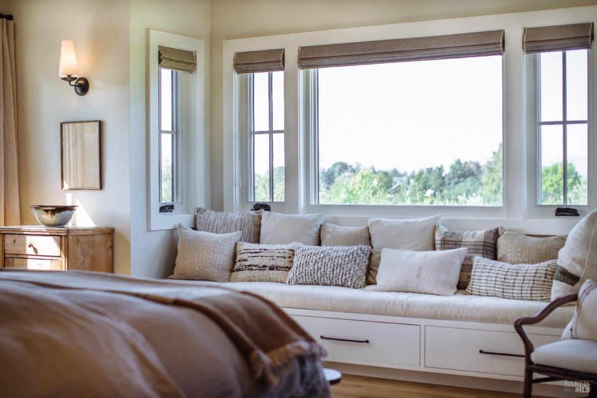 Bedroom corner with built-in window seating and cushions.