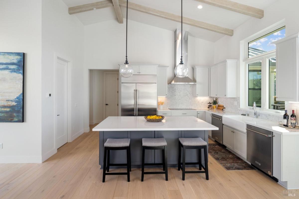 A kitchen with a central island, pendant lighting, and stainless steel appliances.