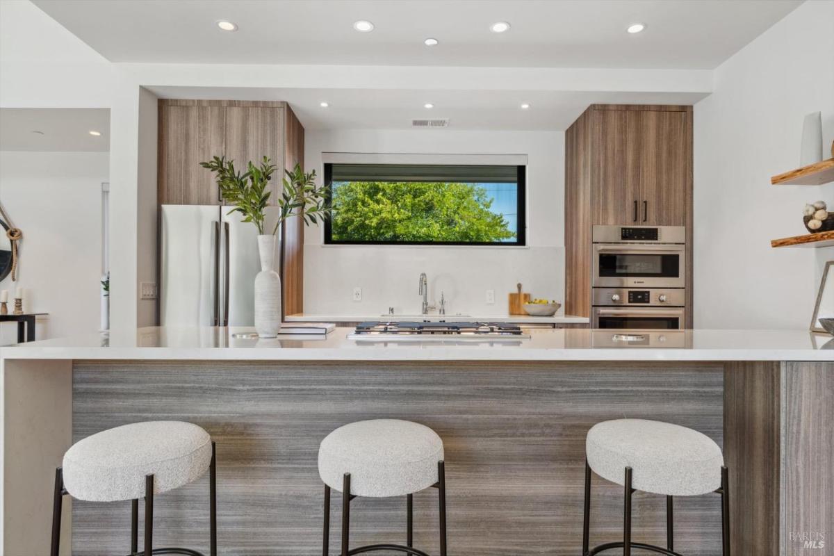 Kitchen with a central island, barstools, and built-in appliances.