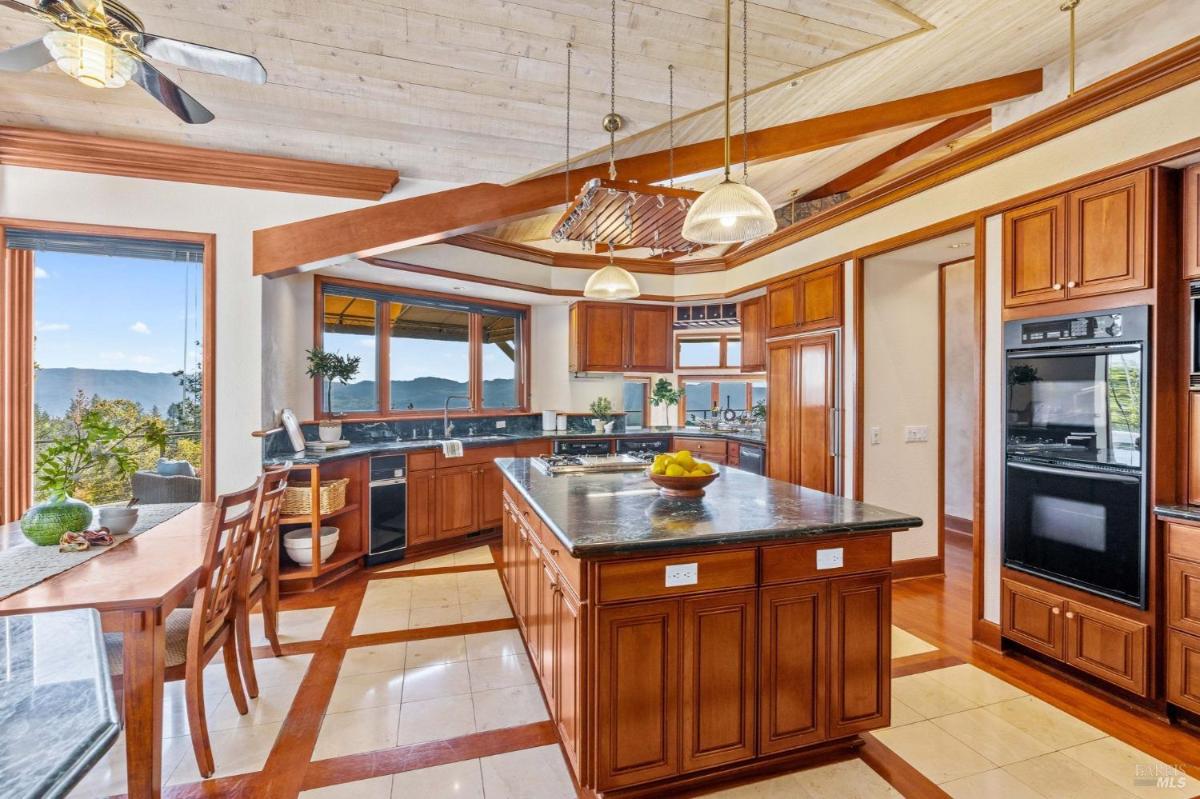 A kitchen with wooden cabinets, an island, and large windows.