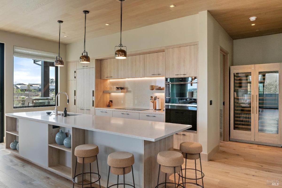 A view of a dining and kitchen space with a large central island and pendant lights.