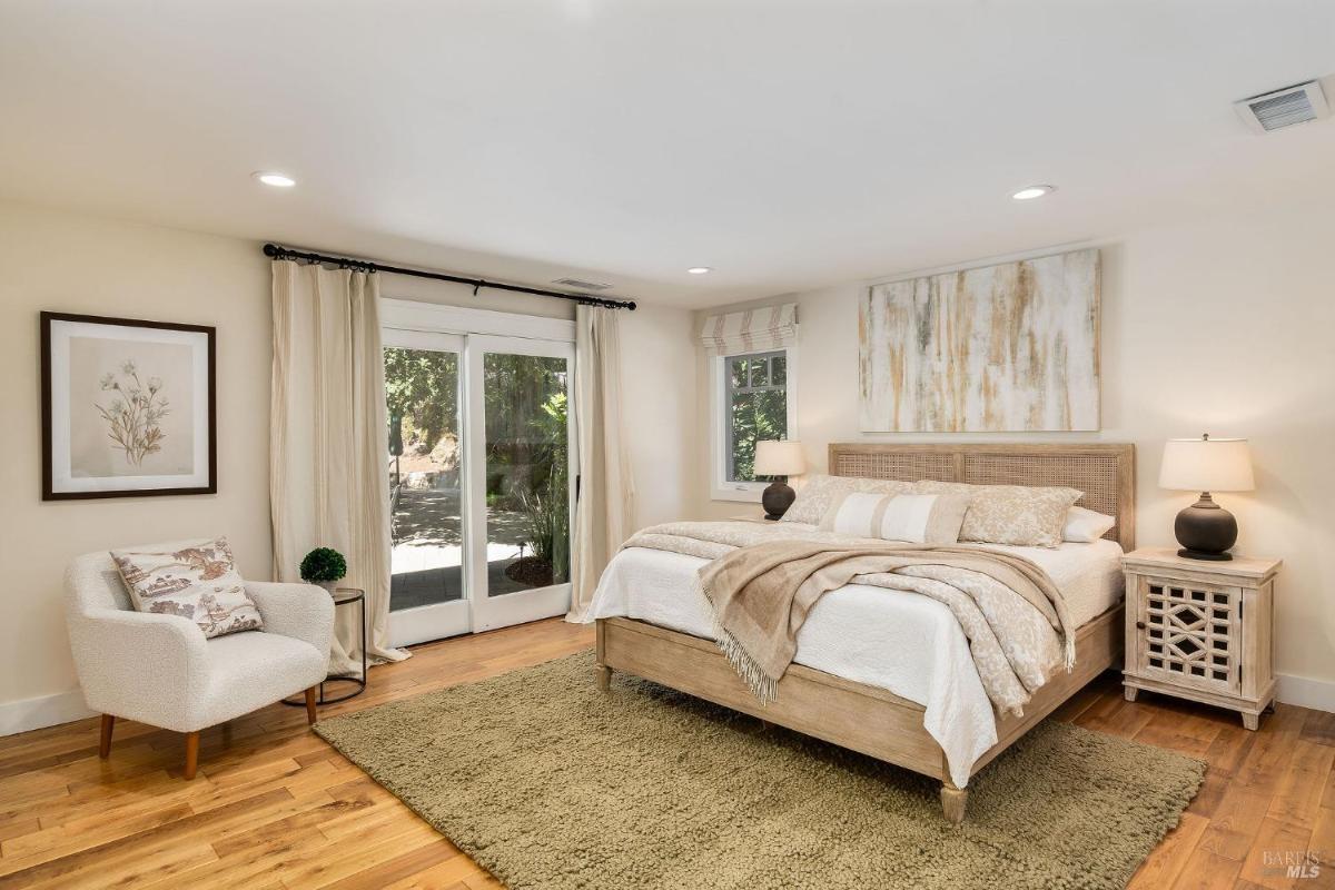 A bedroom with a bed, a chair, and access to a patio through a sliding door.

