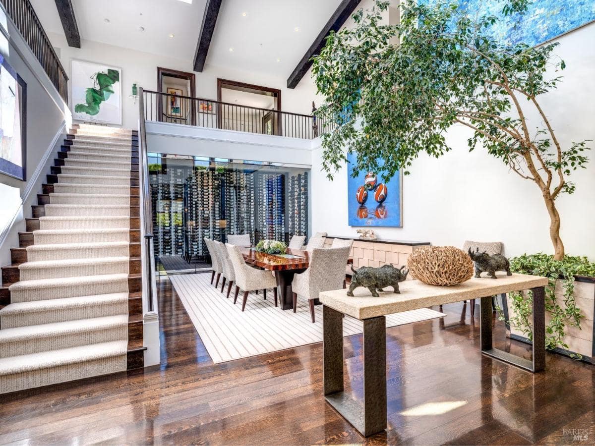 Staircase and dining area with a wine display wall and an open layout.