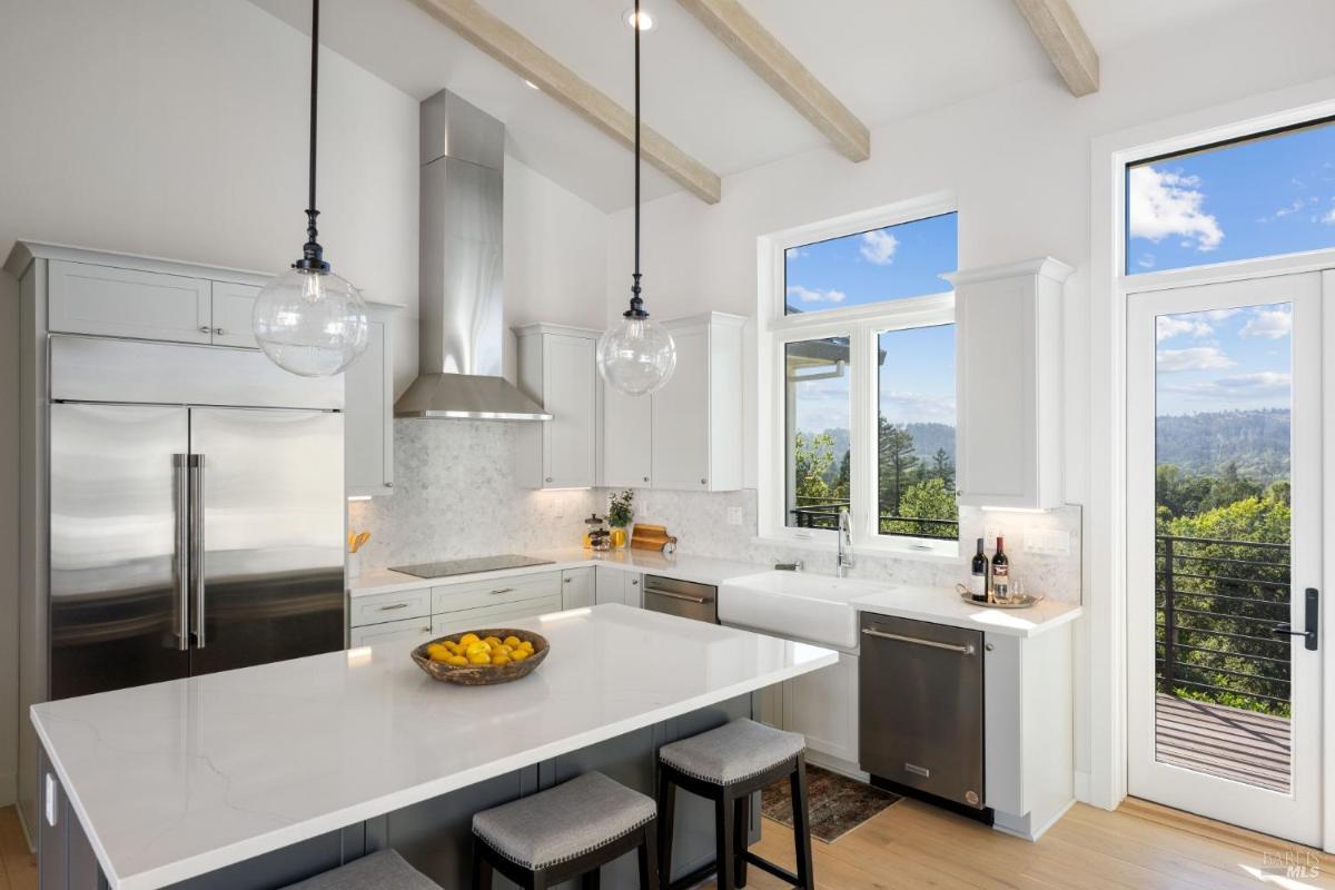 A kitchen with a view through large windows and a door leading to a balcony.