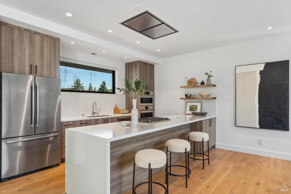 Kitchen with a central island, barstools, and built-in appliances.