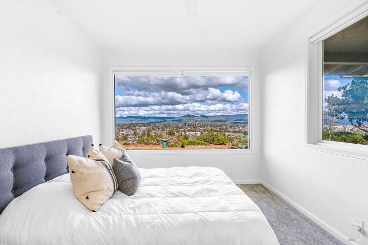 Bedroom with large window overlooking a scenic landscape.