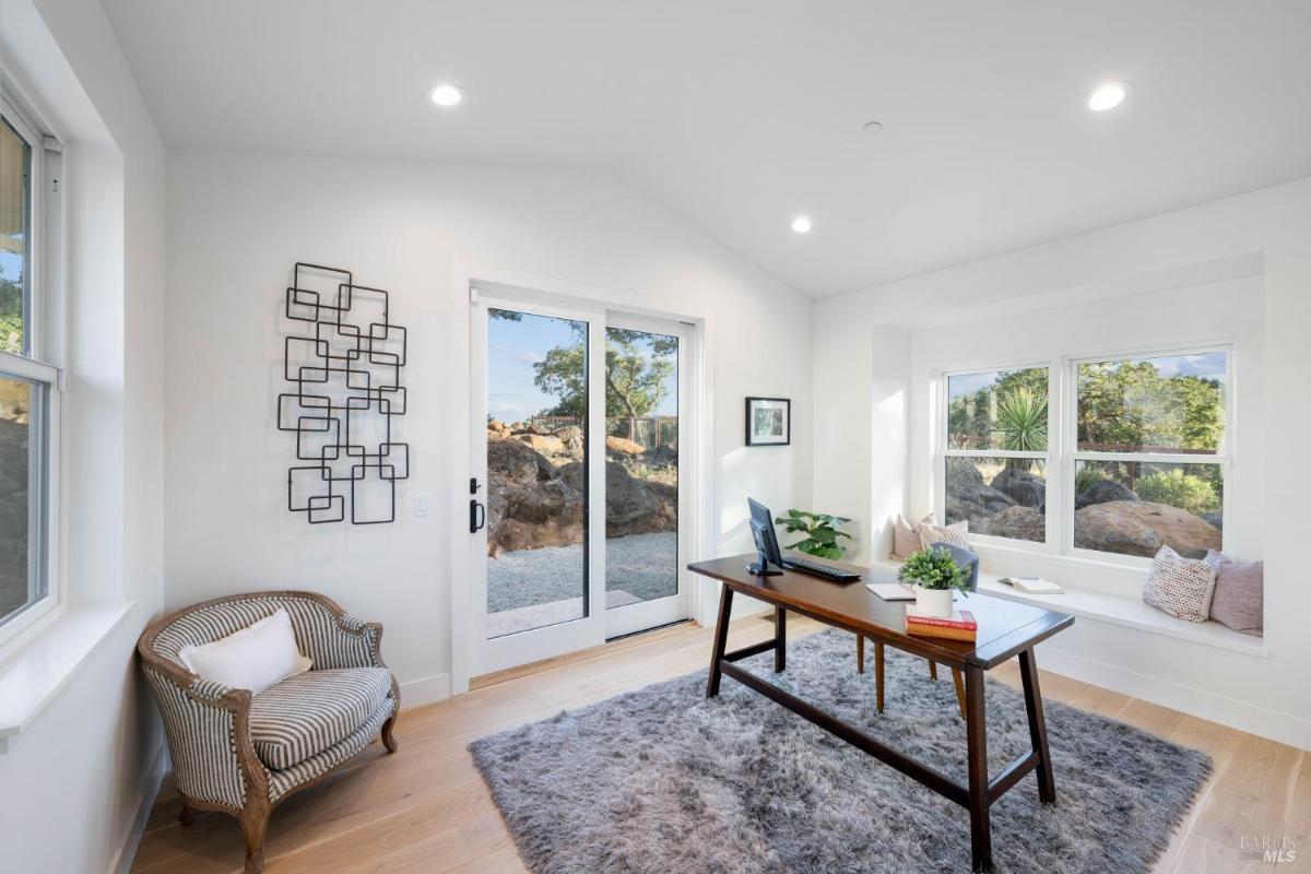 A home office with a desk, a sliding glass door, and built-in seating by the window. 