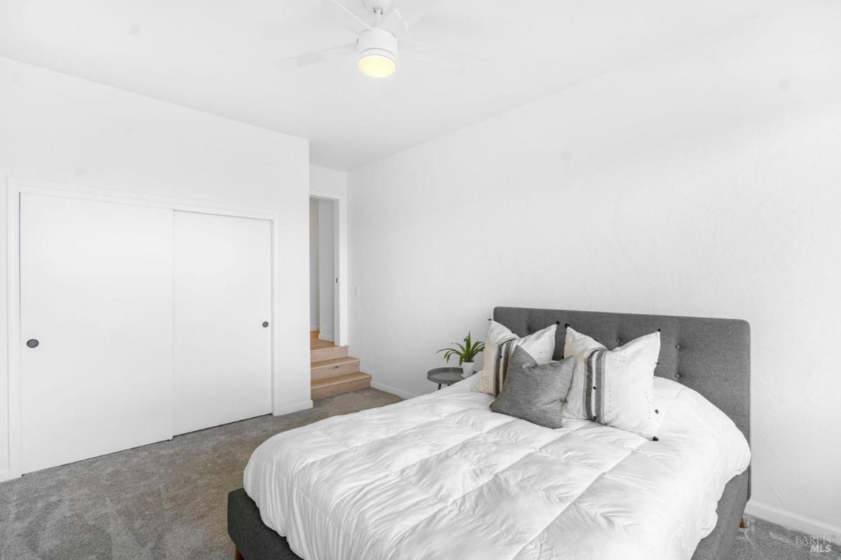 Bedroom with a white bed and closet with sliding doors.