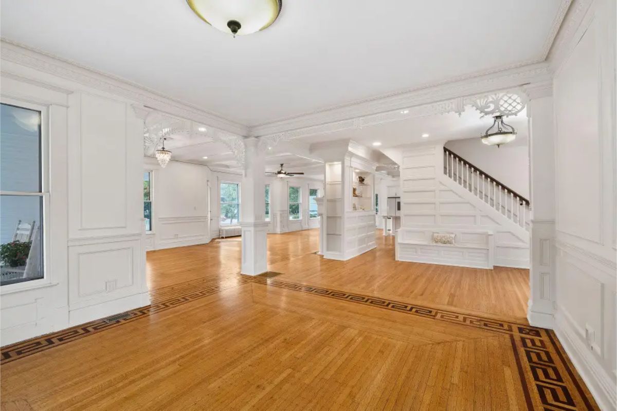 A spacious open living area featuring meticulously restored hardwood floors with detailed inlay work.