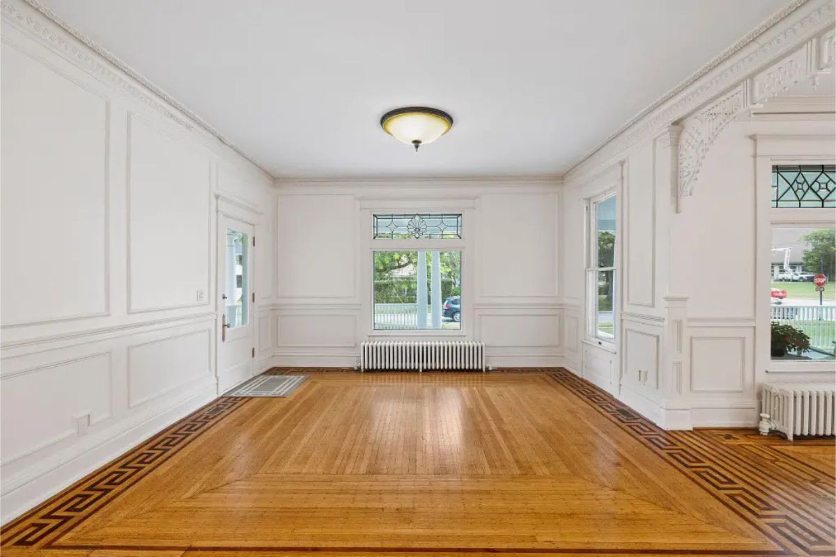 A well-lit room featuring restored hardwood floors with intricate border designs and a neutral color palette.