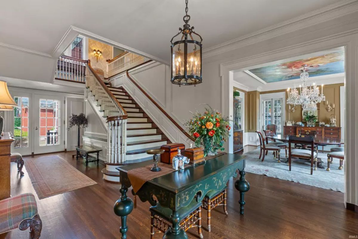 Foyer with a sweeping staircase featuring wooden handrails and white balusters, leading to the upper level. 