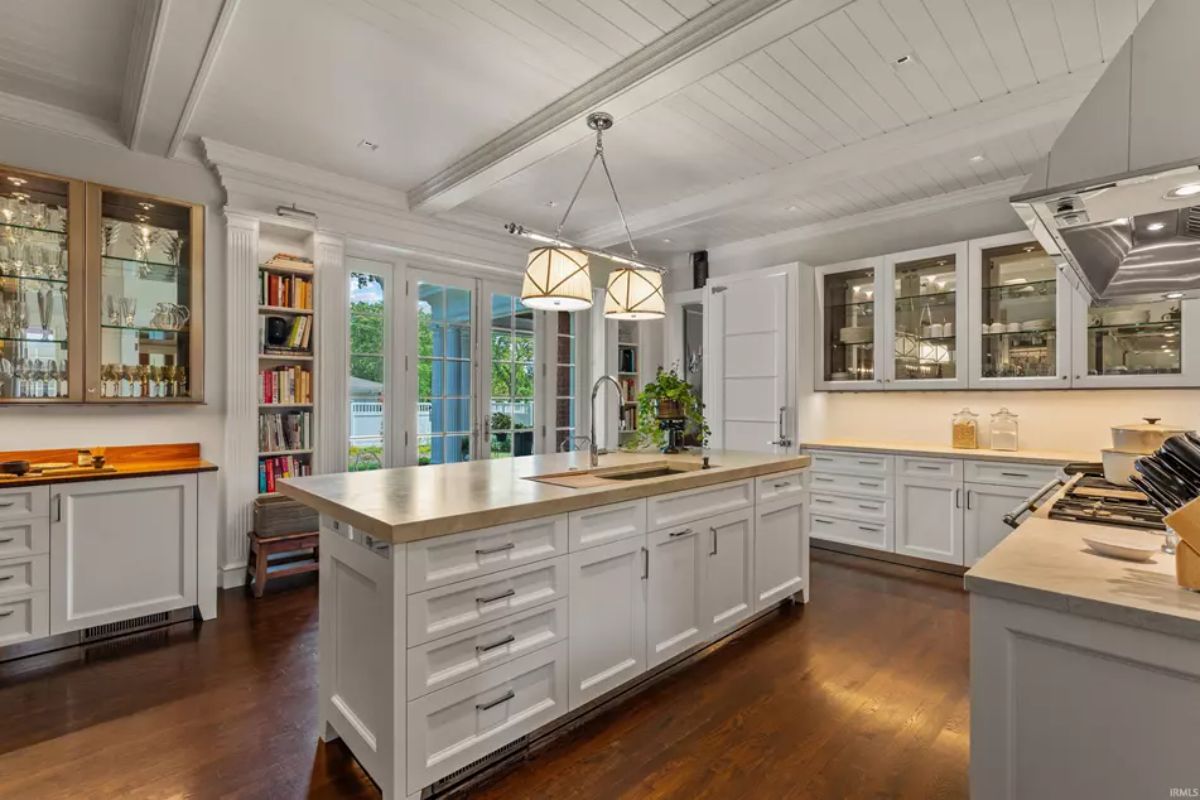 Modern kitchen with white cabinetry, a central island featuring a built-in sink, and wooden countertops.