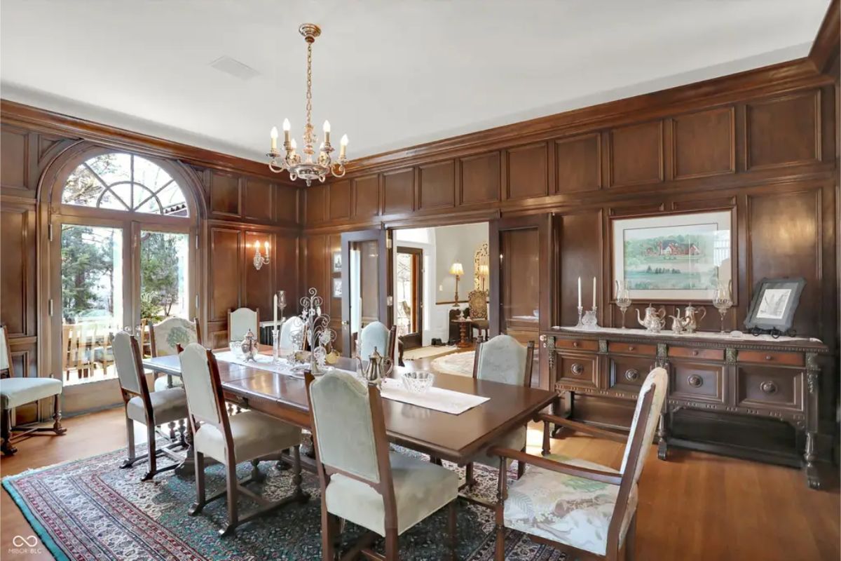 Dining room with rich wood paneling and an arched window that brings in natural light.