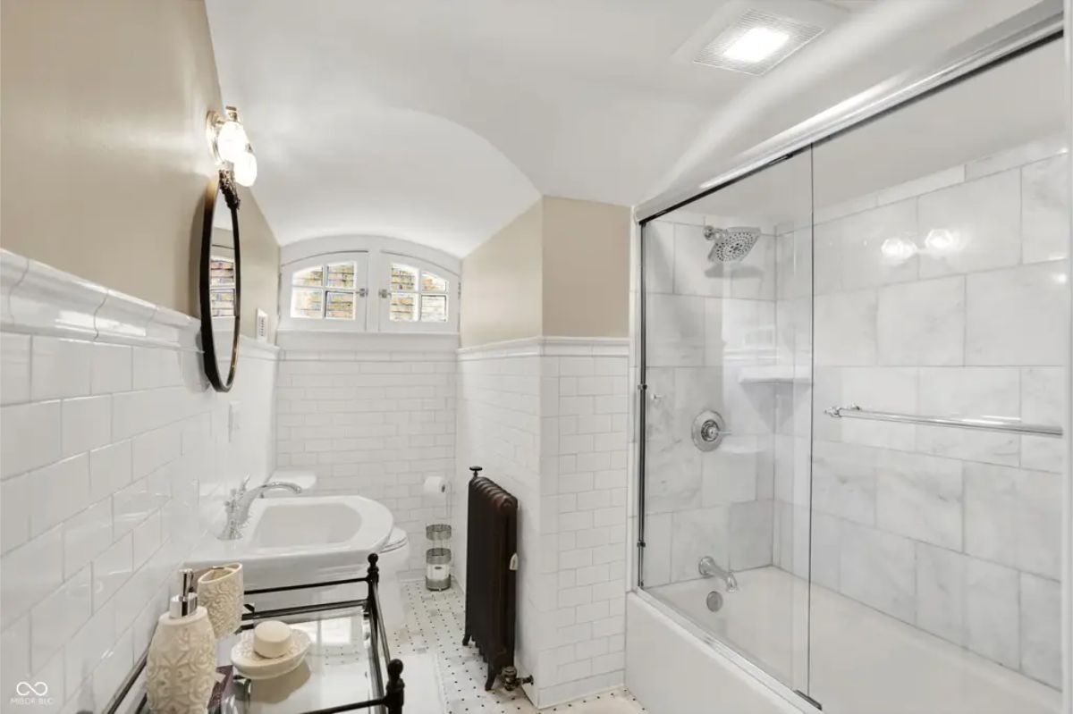 A curved ceiling, subway-tiled walls, and a glass-enclosed marble shower.