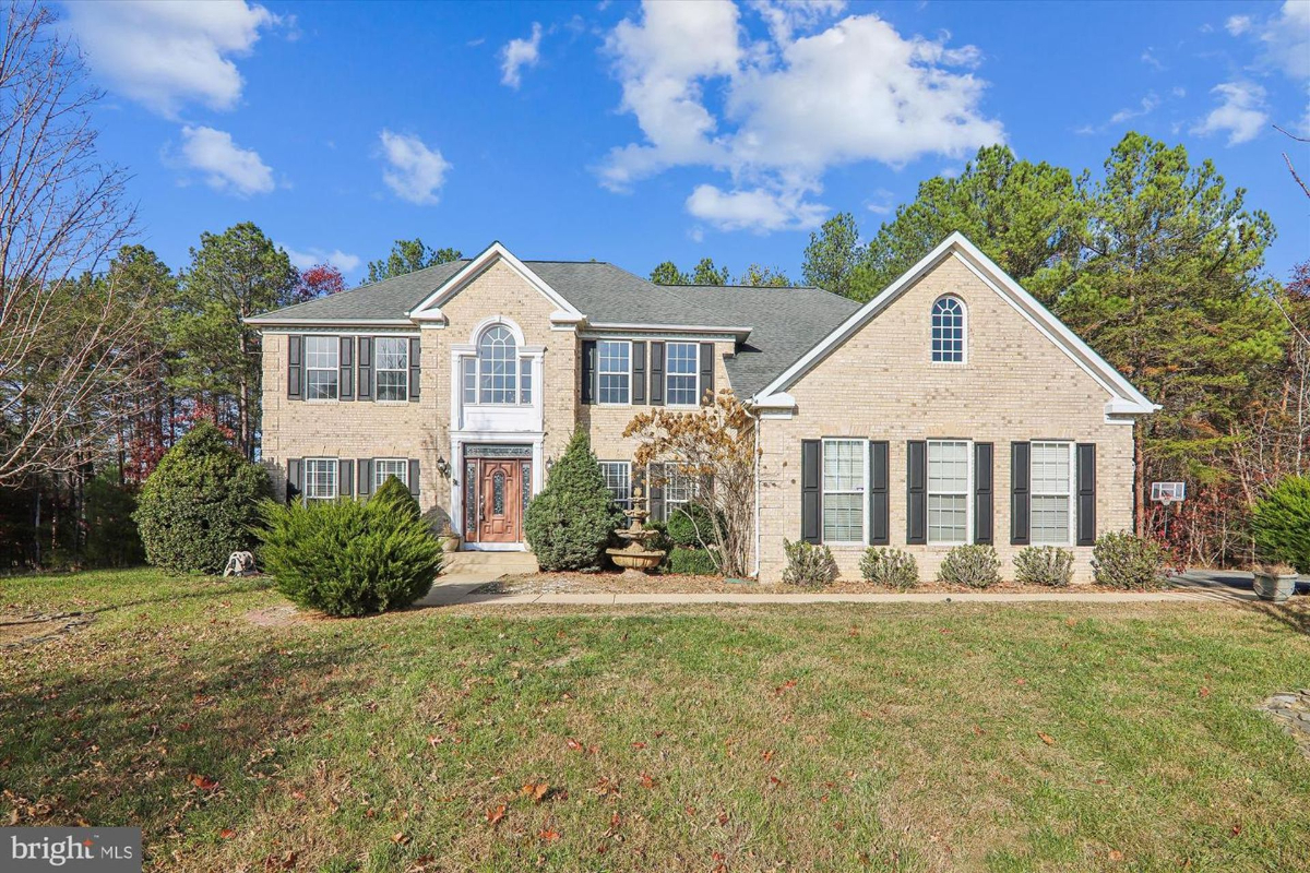 Brick exterior with symmetrical windows and a welcoming front entrance surrounded by manicured shrubs.