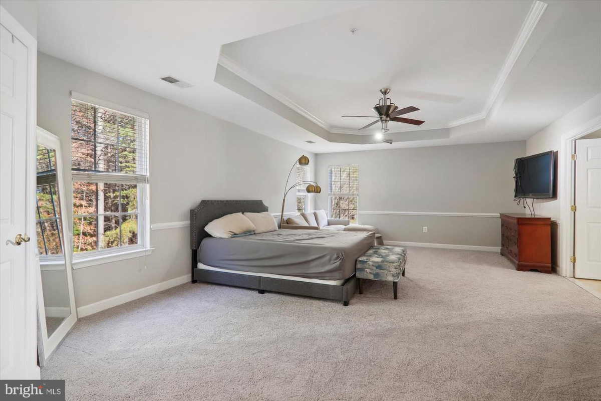 Master bedroom with a large bed, ceiling fan, and carpeted floor.