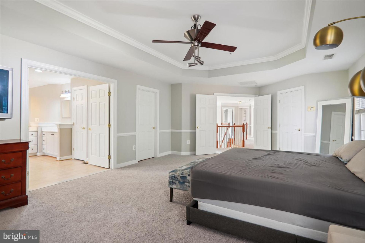 Master bedroom with a large bed, ceiling fan, and carpeted floor.