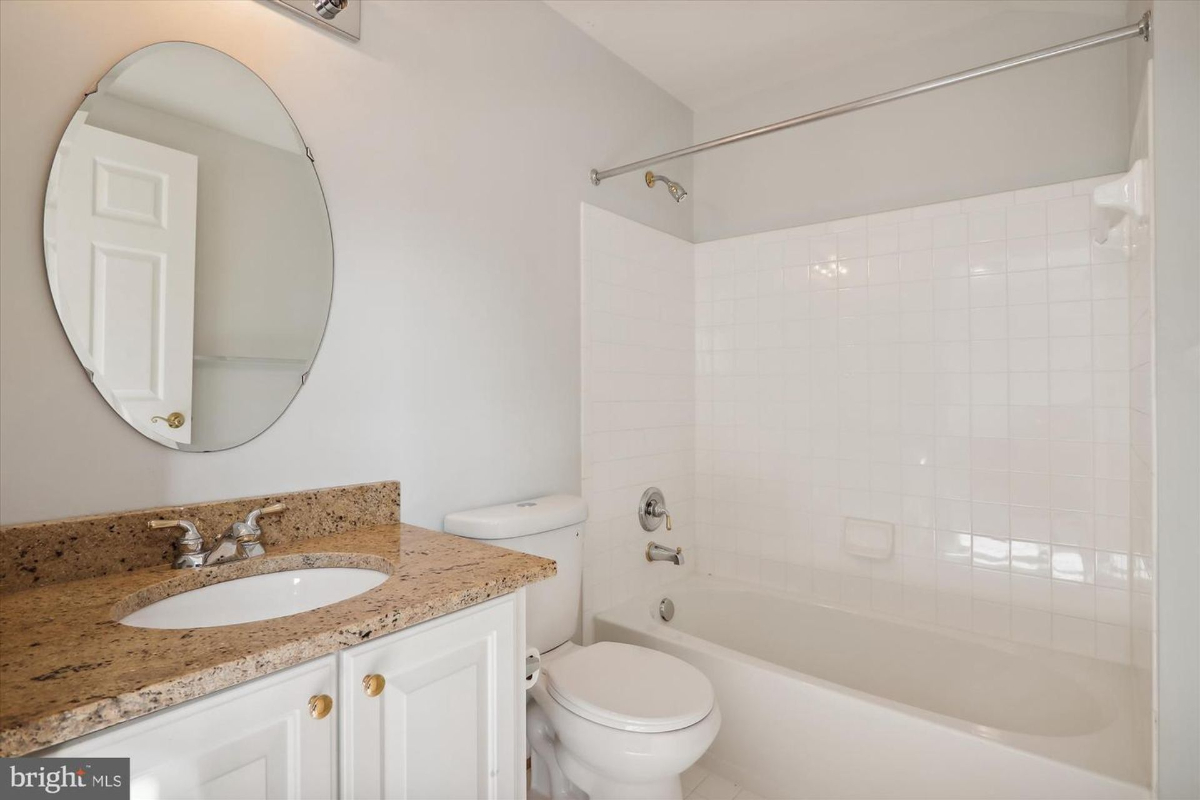 Bathroom with a granite countertop vanity, toilet, and bathtub.