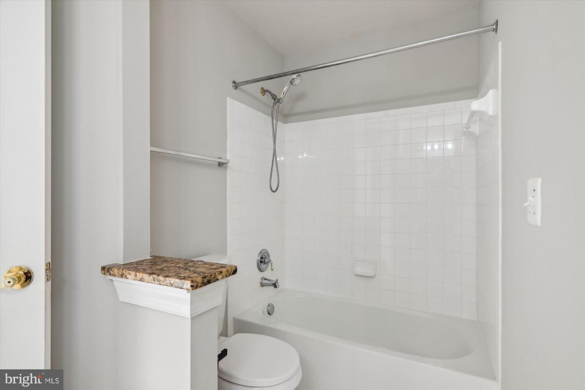 Bathroom with a shower/tub combination, toilet, and granite countertop.