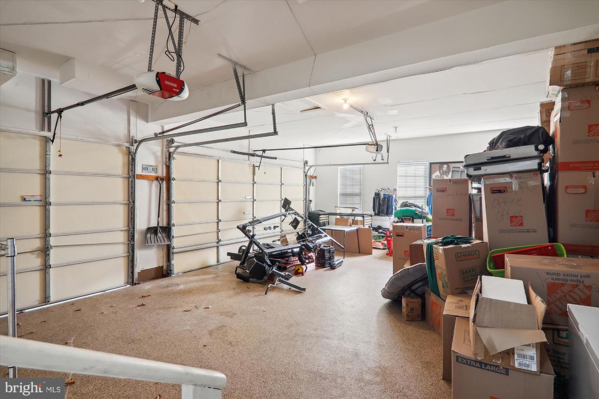 Two-car garage with an automatic garage door opener. The garage is partially filled with moving boxes and other items.