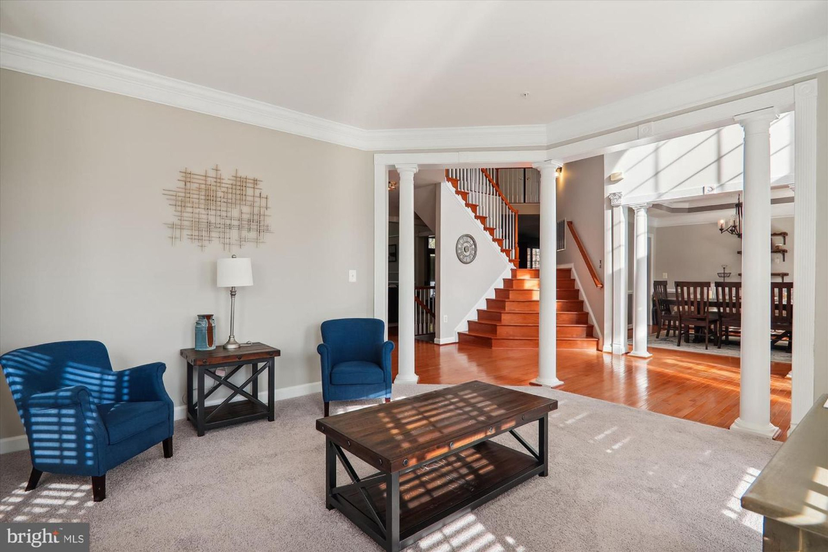 Cozy seating area framed by white columns and open to the grand staircase.