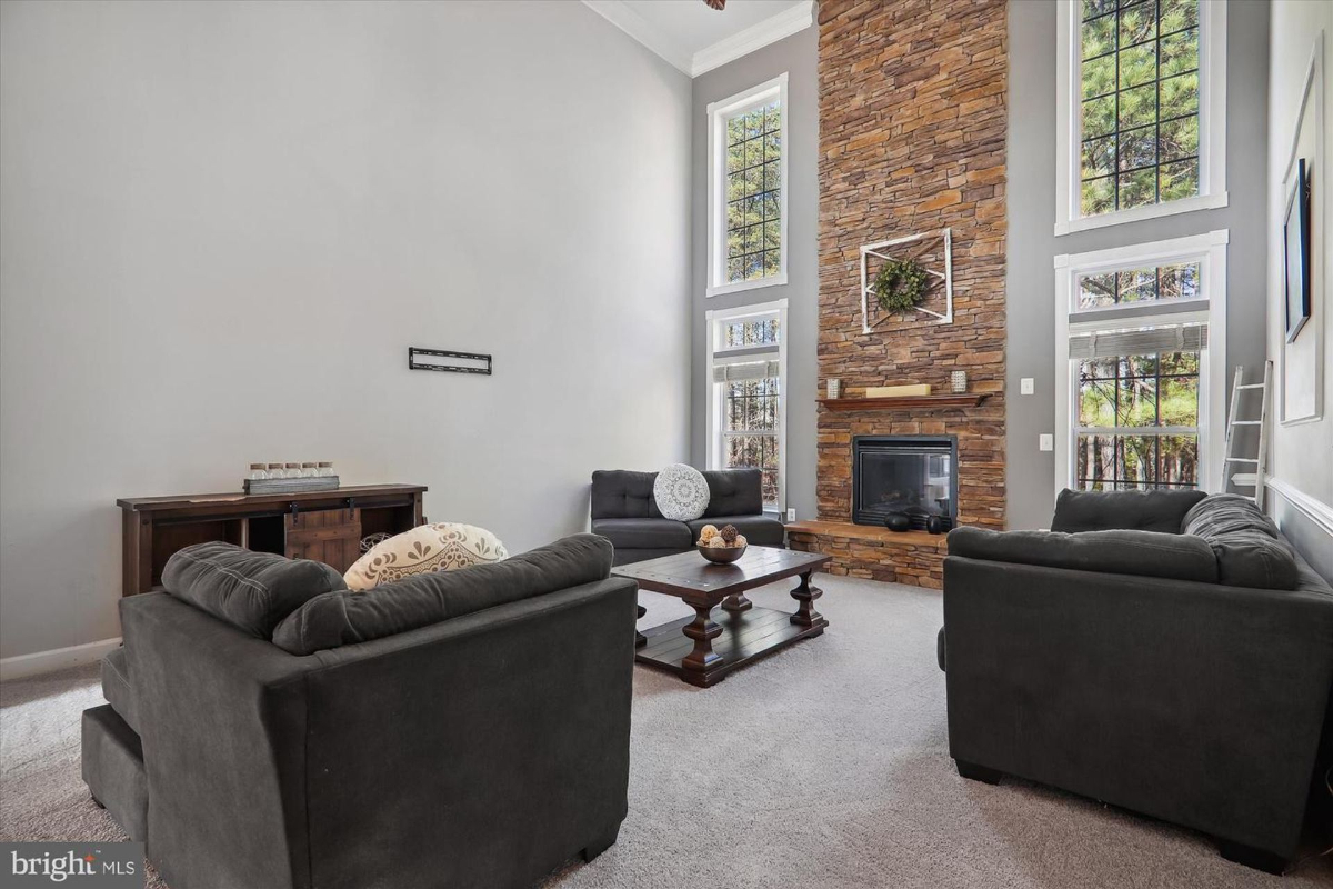 Spacious family room featuring a two-story stone fireplace and large windows.