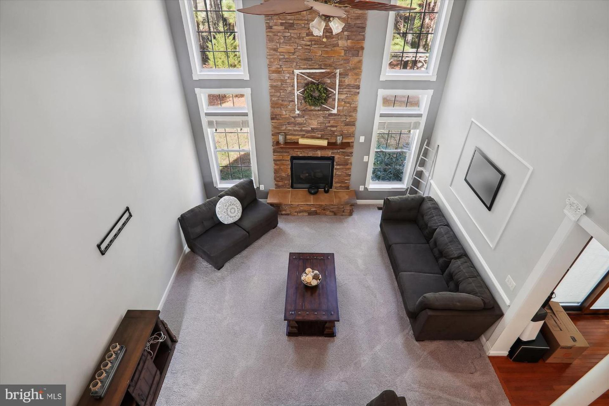 High-angle view of a living room with a stone fireplace and large windows.