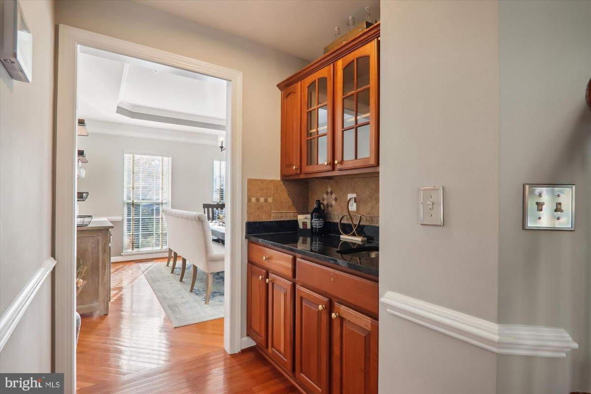 Convenient butler’s pantry with granite counters and wooden cabinetry.