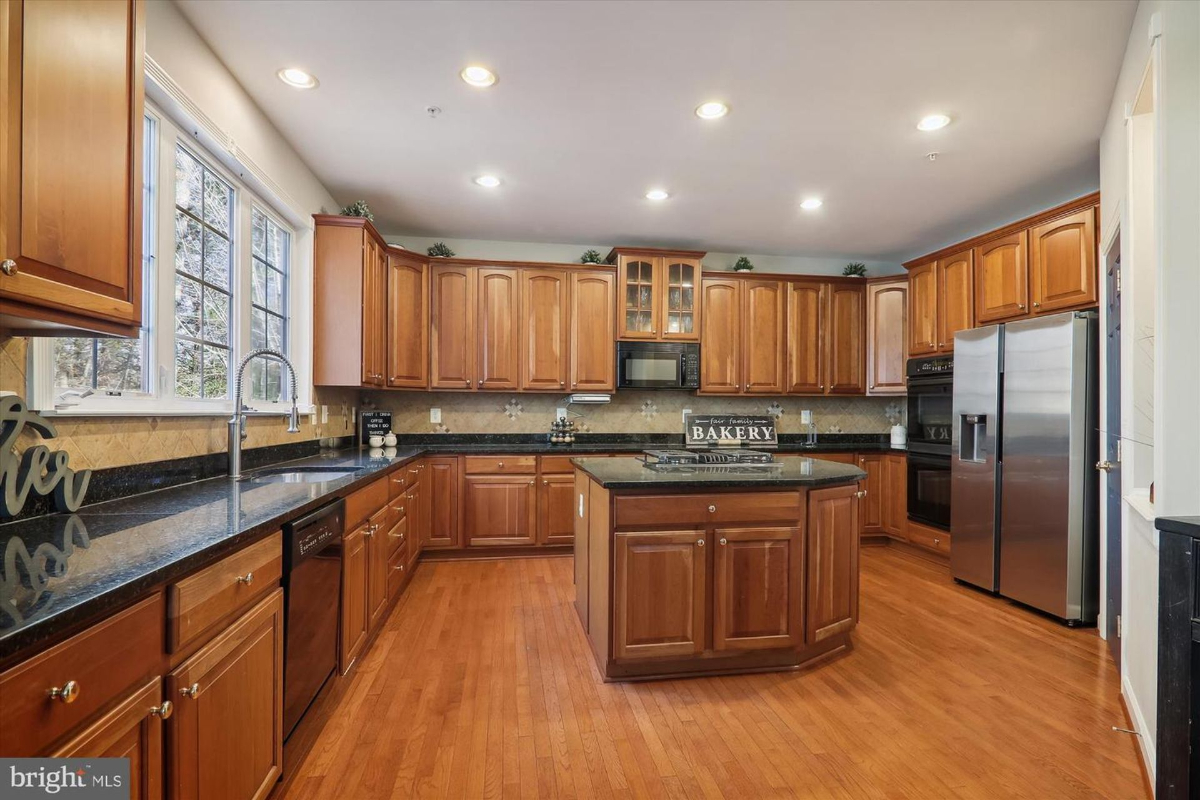 Kitchen with island, stainless steel appliances, and view of staircase.