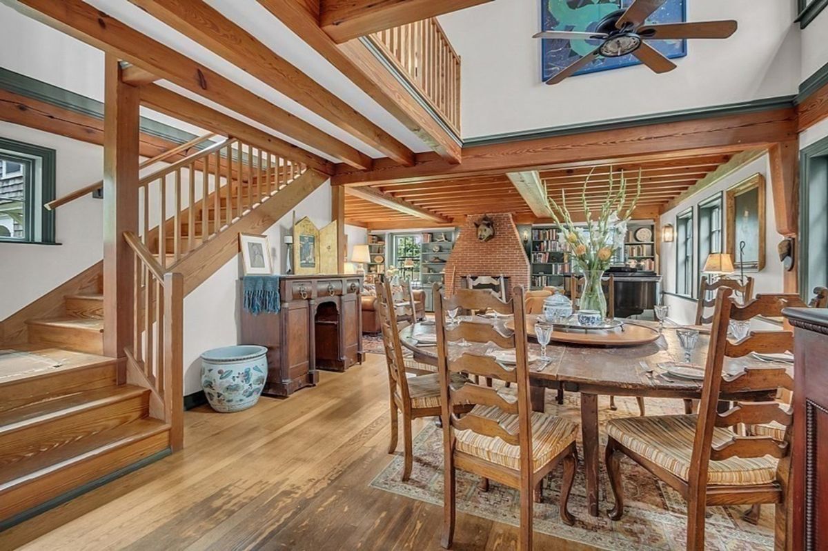 Open dining and living area with rustic wooden ceiling beams and a cozy fireplace.