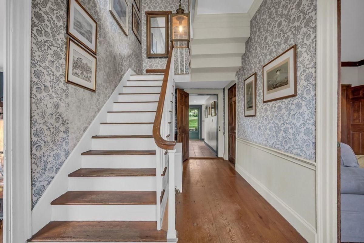 Elegant staircase with classic wooden railing and patterned wallpaper.