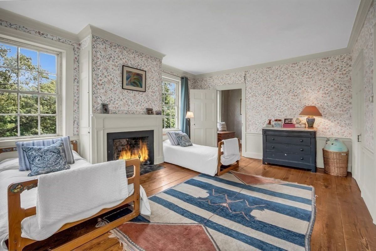 Inviting bedroom with floral wallpaper and a warm fireplace.