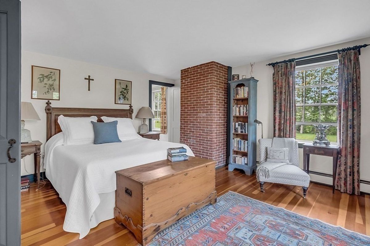 Cozy primary bedroom with exposed brick, a sitting area, and large windows.