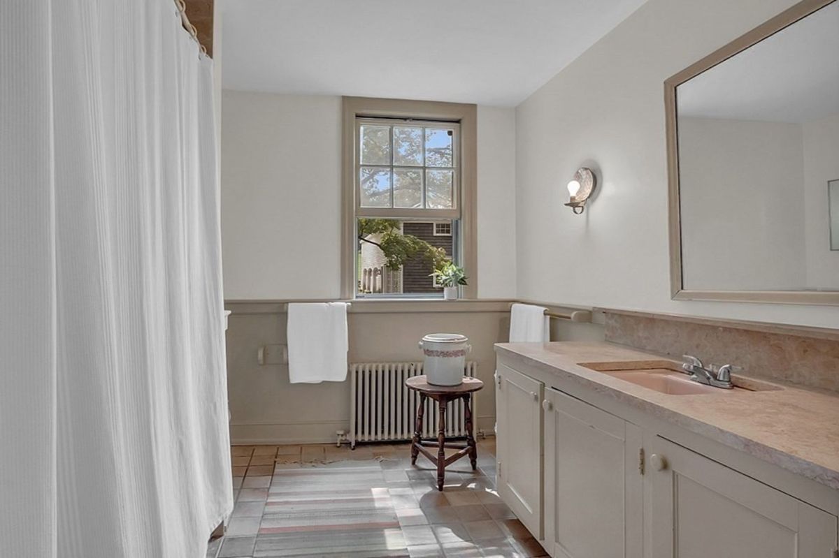 Spacious bathroom featuring a large vanity, vintage accents, and a tiled floor.