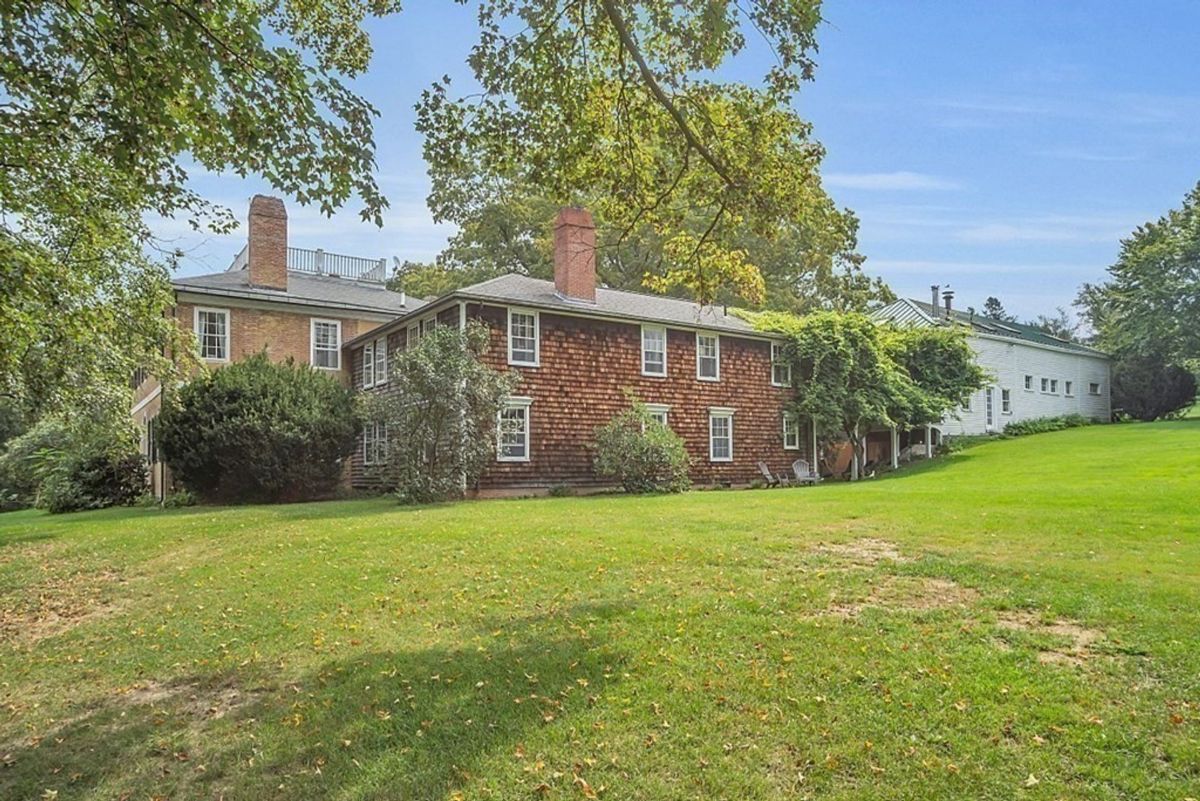 Back view of a charming home surrounded by lush greenery.