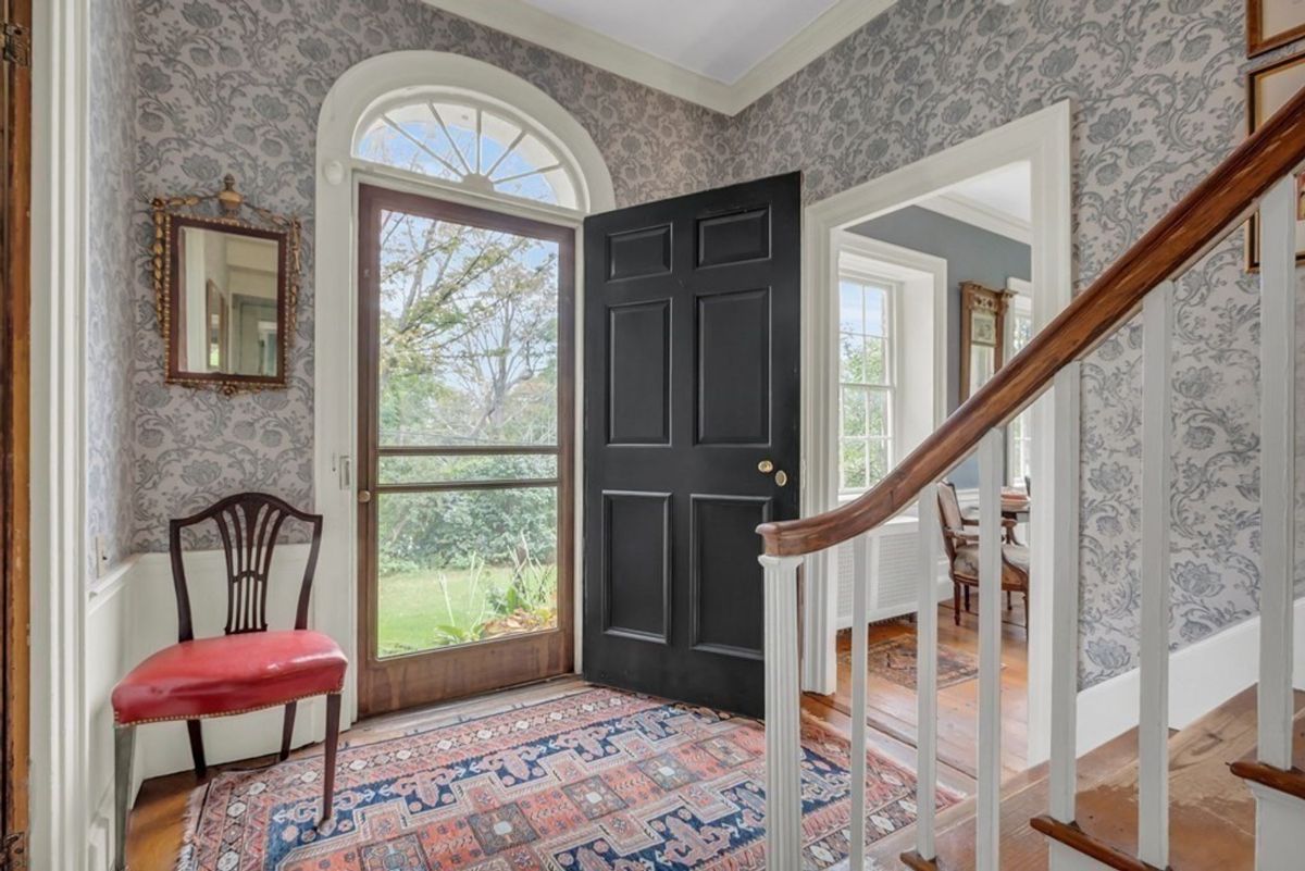 Entryway features patterned walls, dark door, and a staircase.