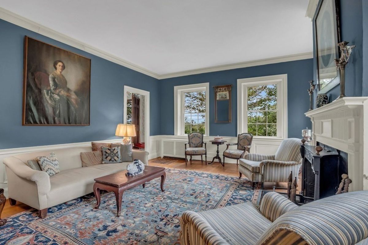 Formal sitting area features blue walls, hardwood floors, and patterned furnishings.