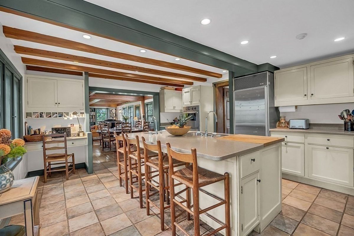 Spacious kitchen featuring a large island with bar seating and exposed wooden beams.