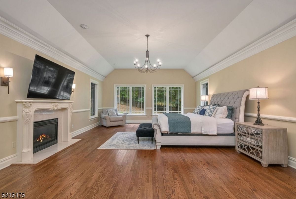 Elegant primary suite showcases a cozy fireplace, vaulted ceilings, and serene woodland views.