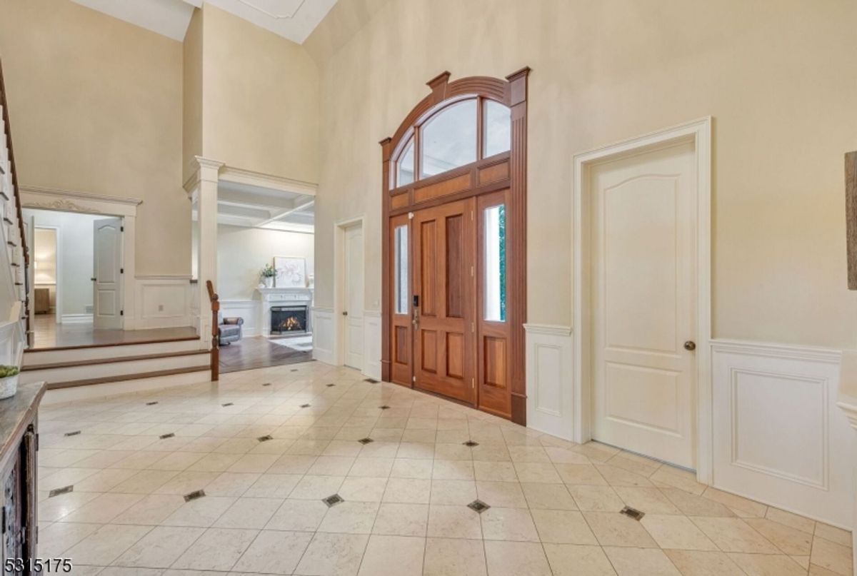 Expansive foyer showcases soaring ceilings, tiled flooring, and a statement wooden entry door.