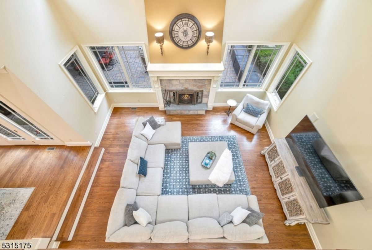 A grand two-story family room showcases a cozy fireplace, expansive windows, and an inviting sectional seating arrangement.