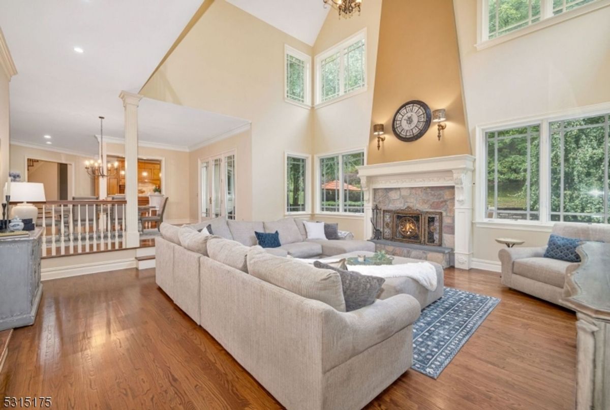 Living room showcases a soaring ceiling, a grand fireplace, and expansive windows that flood the space with natural light.