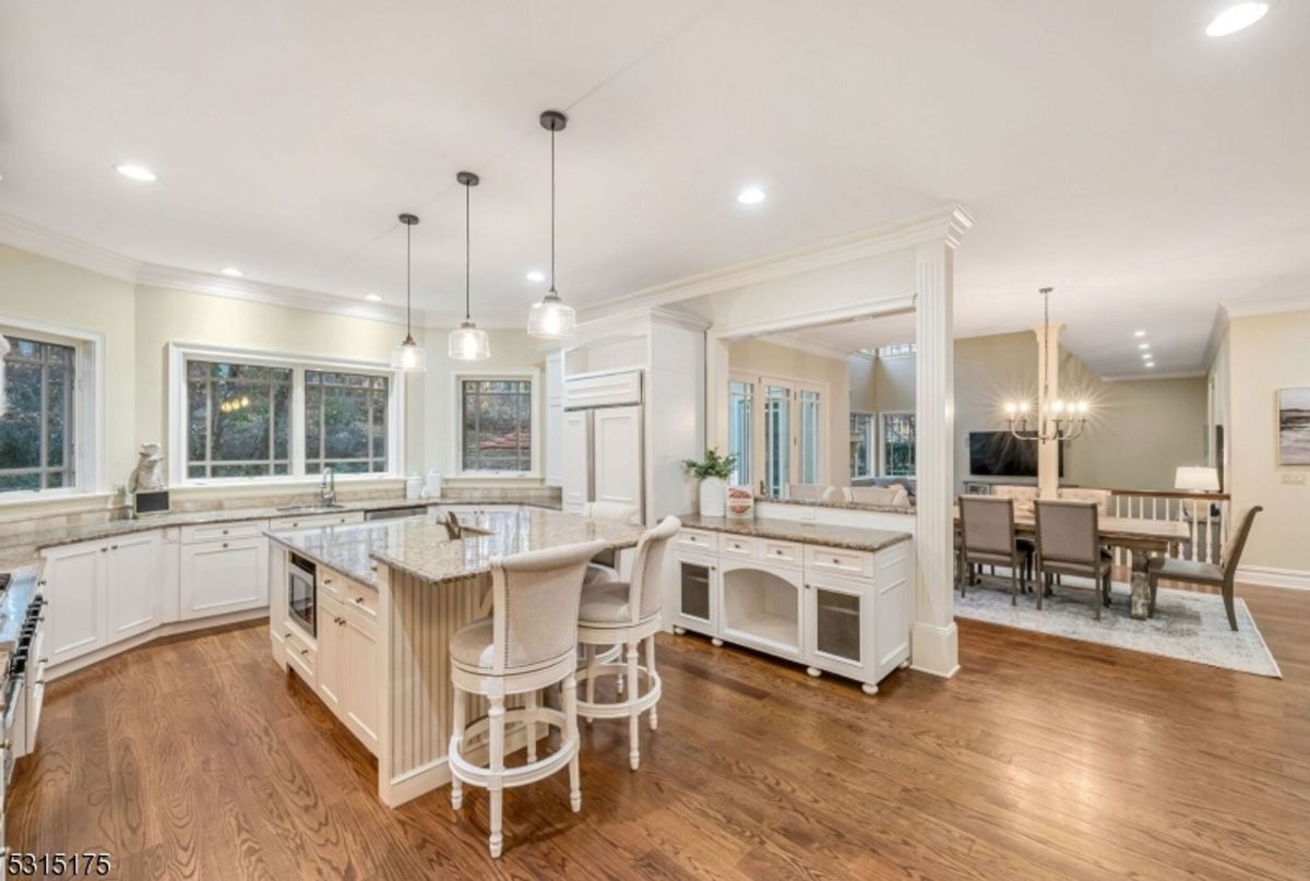 Gourmet kitchen features a large center island, granite countertops, and elegant pendant lighting.