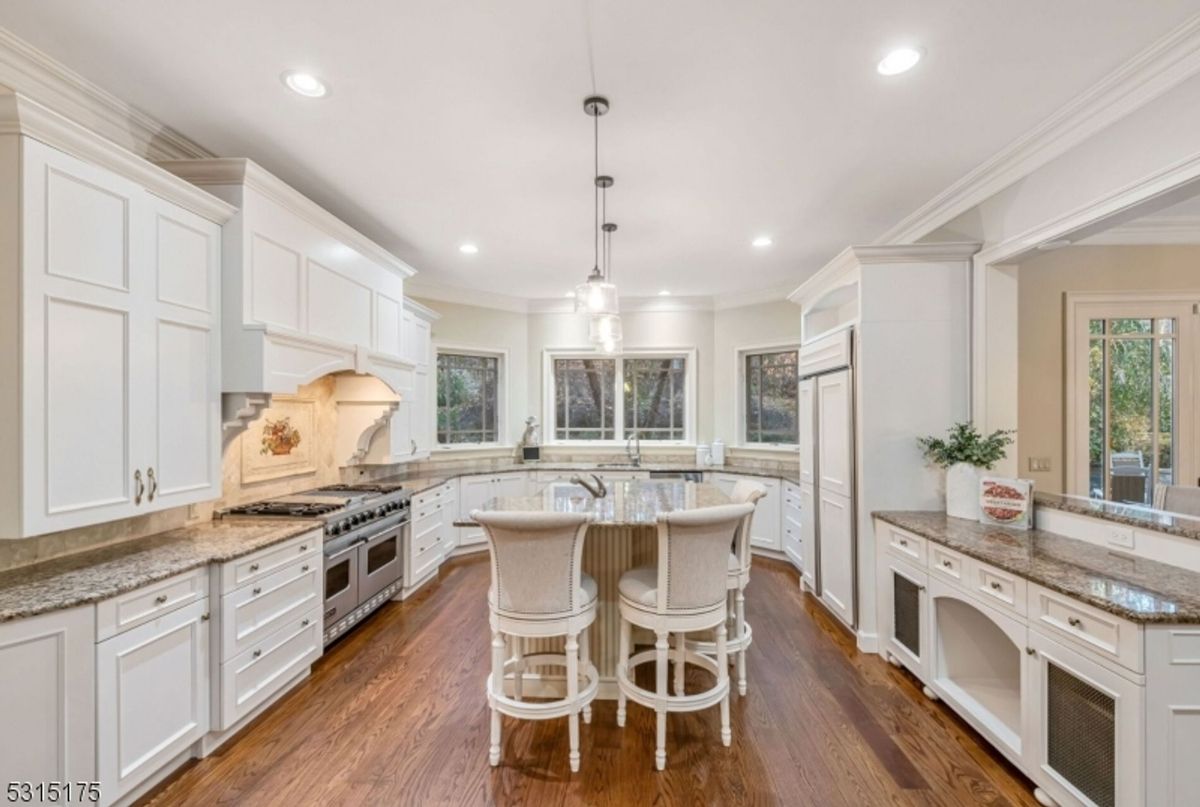 A gourmet kitchen showcases pristine white cabinetry, granite countertops, and a professional-grade stove.