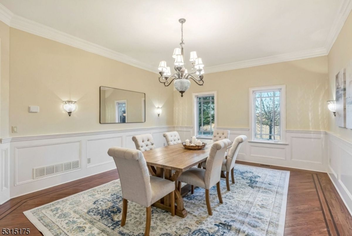 Elegant dining space highlights a wooden table, chandelier, and serene natural light.