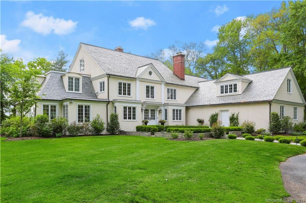 Large white house on a green lawn.