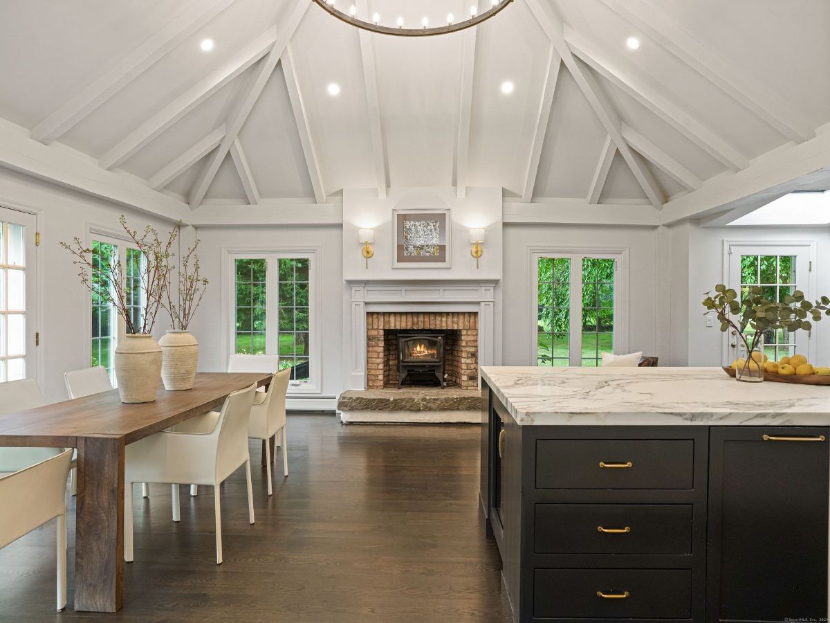 Elegant dining area with exposed beams, a brick fireplace, and a marble-topped island.