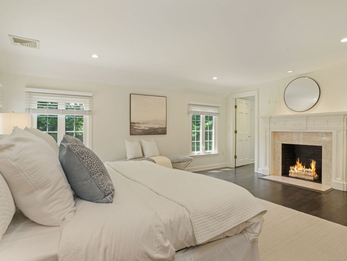 Inviting bedroom with a fireplace, soft bedding, and serene natural light.