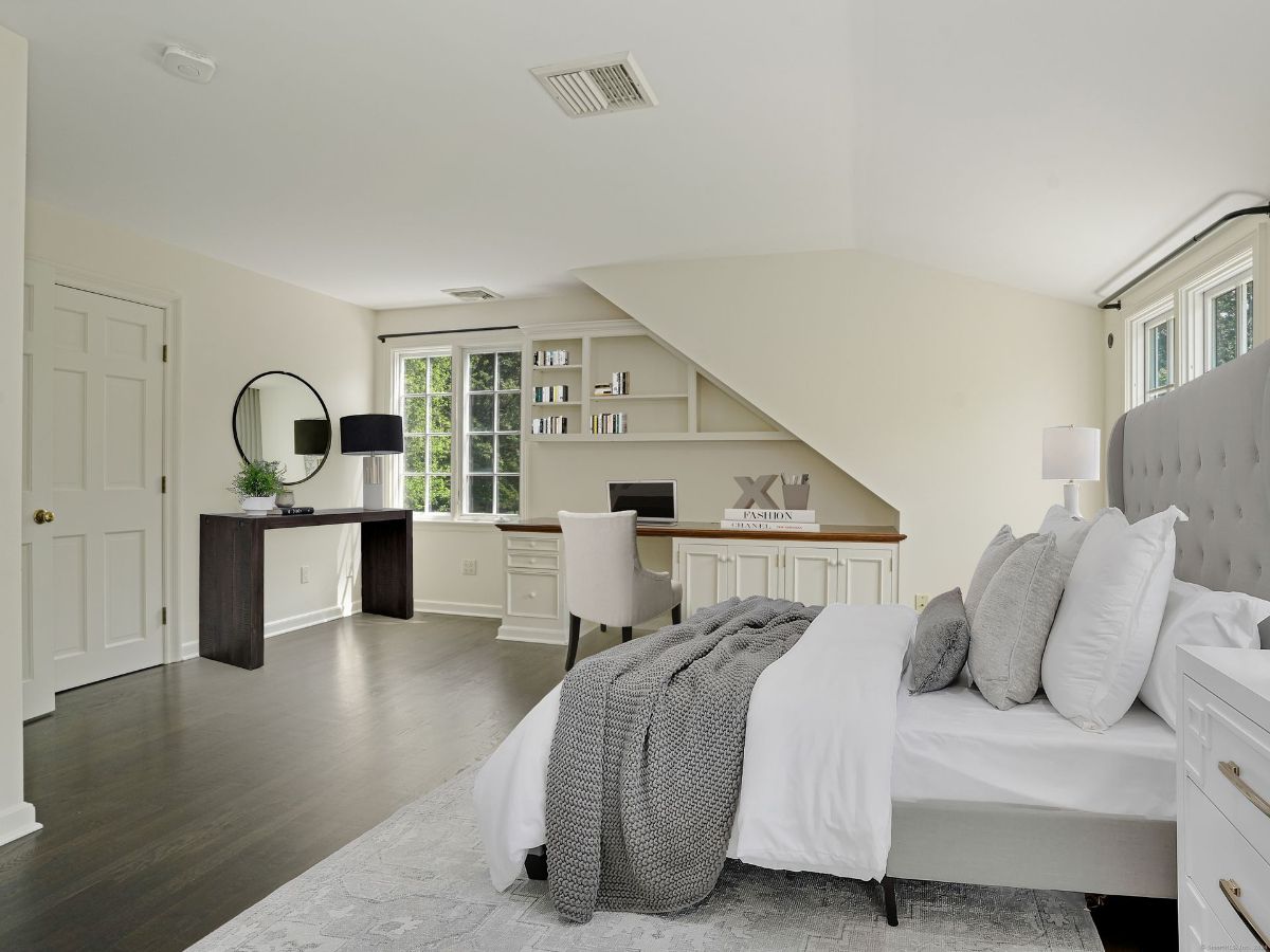 Charming bedroom with a built-in desk, shelving, and large windows for natural light.